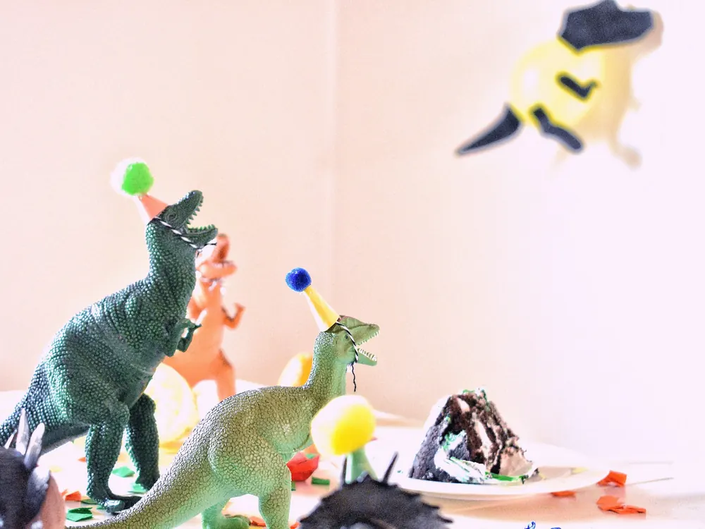 Dinosauři v narozeninových čepičkách na slavnostním stole